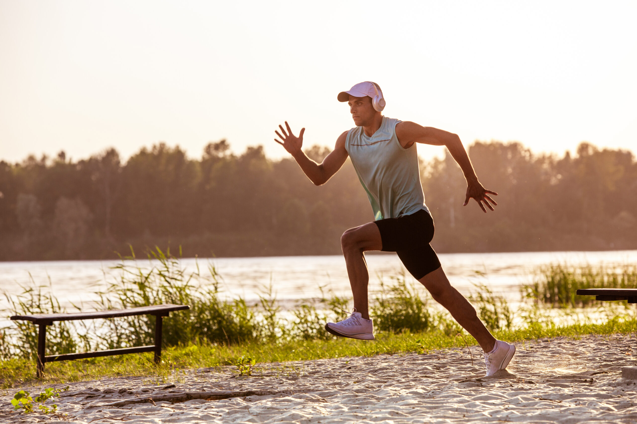 A young athletic man working out listening to the music at the riverside outdoors