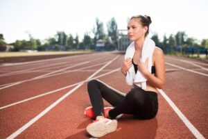 beautiful-girl-wireless-earphones-with-white-towel-neck-dreamily-looking-aside-treadmill-city-stadium_574295-5949