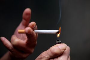 A closeup shot of a person lighting a cigarette in front of a black background