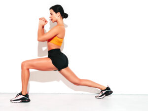 Portrait of fitness confident woman in black sports clothing. Sexy young beautiful model with perfect body. Female isolated on white wall in studio. Stretching out before training. Doing lunges Portrait of fitness confident woman in black sports clothing. Sexy young beautiful model with perfect body. Female isolated on white wall in studio. Stretching out before training. Doing lunges