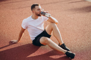 Young sportsman drinking water at stadium